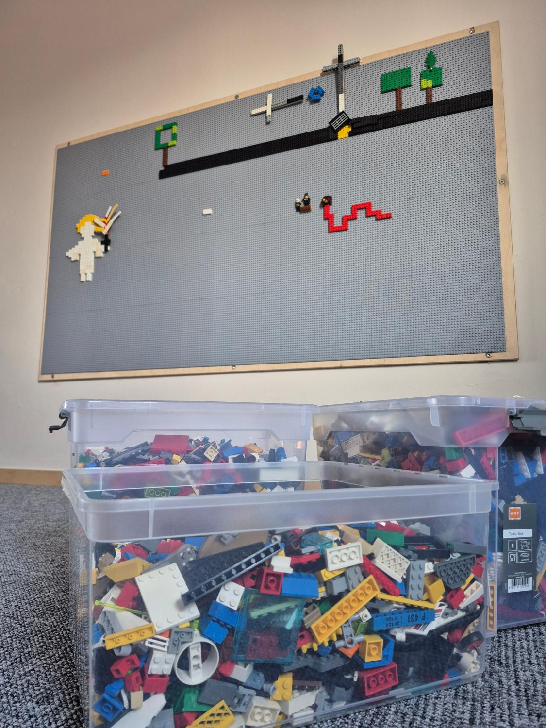 Ansicht auf Legowand mit 4 Kisten voll mit Lego im Vordergrund