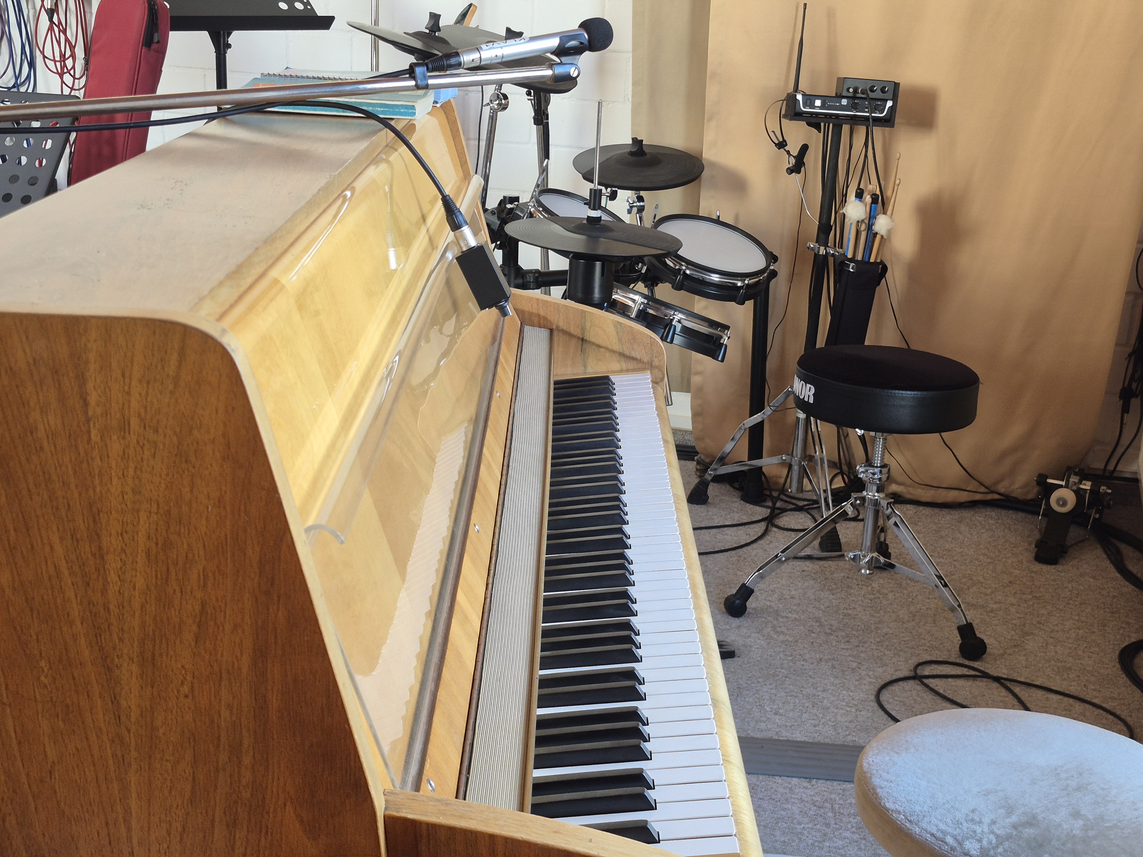 Seitliche Ansicht eines Klaviers mit einem E Schlagzeug im Hintergrund